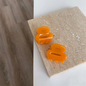Vue détaillée de deux mini pinces à cheveux orange en acétate faites à la main
