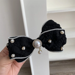 Elegant black fabric bow hair clip with faux pearls and rhinestones on a white background