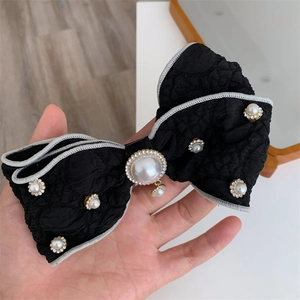 Close-up of black fabric bow hair clip with faux pearls and rhinestone embellishments
