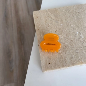 Vue détaillée de la pince à cheveux en acétate orange avec inscription fait main