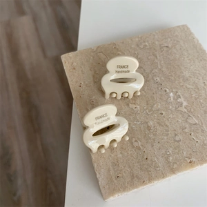 Vue détaillée de petites pinces à cheveux en acétate beige avec gravure France Handmade