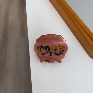 Détail d'une pince à cheveux rose motif chien avec lunettes en forme de cœur