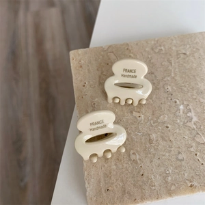Détail de mini pinces à cheveux en acétate crème avec logo France Handmade sur pierre
