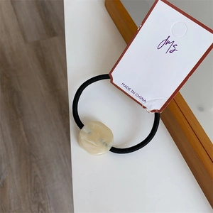 Close-up of cream marble resin bead on a high-elastic black hair tie with display card