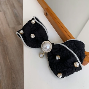Close-up of black fabric bow hair clip with faux pearls and rhinestone details
