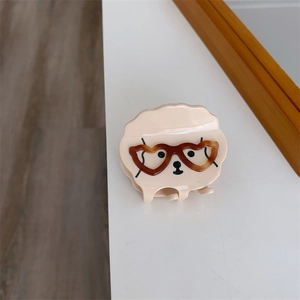 Détail d'une pince à cheveux en forme de chien mignon en acétate crème avec des lunettes