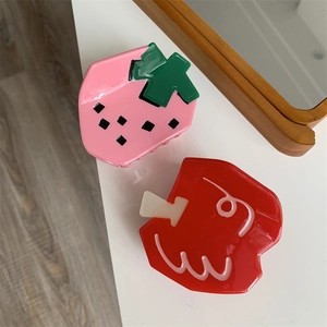 Detailed view of pink strawberry and red fruit claw clips with a glossy acetate finish