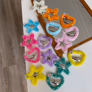 Dettaglio di fermagli in peluche a forma di cuore e stella con strass colorati