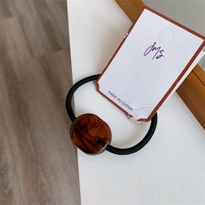 Detail of high-elastic black hair tie featuring a polished brown amber textured resin bead