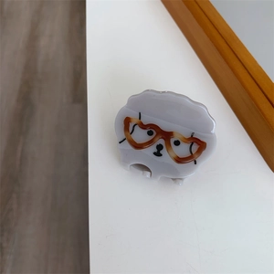 Détail d'une pince à cheveux agneau gris avec lunettes marron sur une surface blanche