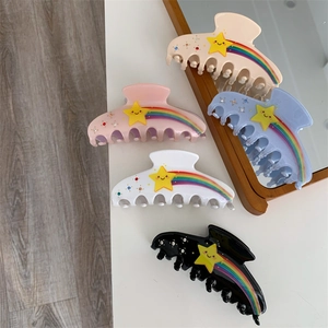 Detailed view of five acetate hair claws with rainbow stripes and rhinestone star accents