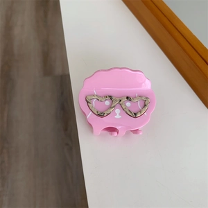 Détail de la pince à cheveux en acétate rose avec lunettes en forme de cœur léopard