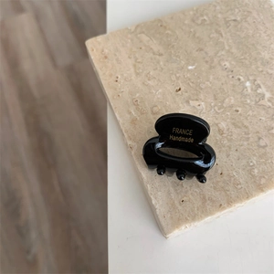 Détail d'une pince à cheveux en résine noire brillante avec inscription dorée faite main