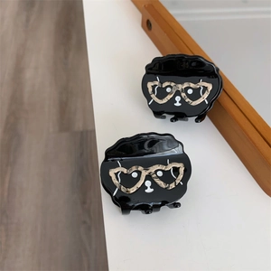 Détail d'une pince à cheveux chat noir avec des lunettes coeur en écaille de tortue