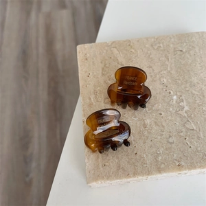 Vue détaillée de petites pinces à cheveux en acétate marron écaille avec logo doré