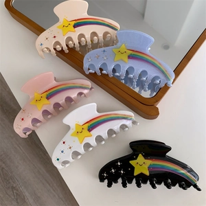 Detailed close-up of acetate shark clips with rainbow patterns and smiley star rhinestones