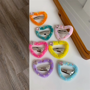 Dettaglio di fermagli per capelli a cuore in peluche colorato con strass e stelle