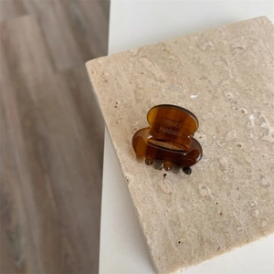 Gros plan sur une petite pince à cheveux en acétate écaille avec lettrage doré