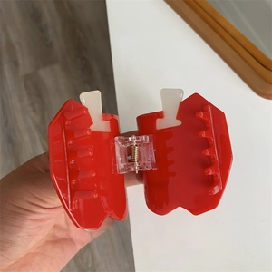Detailed view of apple-shaped hair claw clip in red and cream with spring mechanism