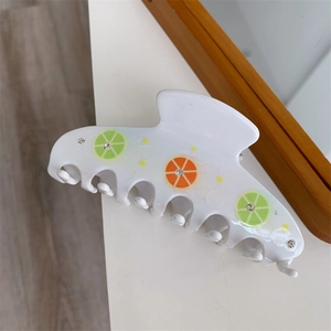 Detail of white acetate hair claw clip with colorful lemon prints and small rhinestones