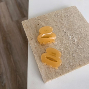 Détail de deux mini pinces à cheveux en acétate ambré avec texte France Handmade sur pierre