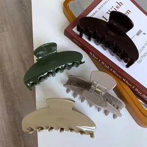 Detailed view of large acetate hair claws in earth tones with gold letter printing