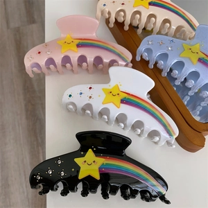 Detailed close-up of colorful claw clips with rainbow stripes and star rhinestone accents