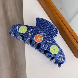 Detail of blue denim-texture hair claw clip with lime, orange patterns and rhinestones