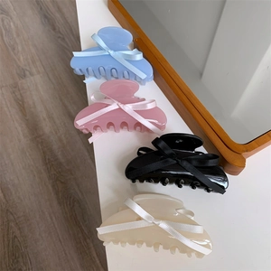 Détail de quatre pinces à cheveux en acétate avec nœuds en bleu, rose, noir et blanc