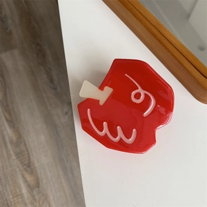 Creative red apple fruit hair claw clip for women on a minimalist white desk with mirror