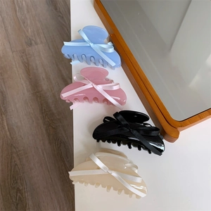 Détail de pinces à cheveux en acétate avec des nœuds sur une surface blanche