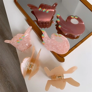 Detail view of Shaka and OK gesture hair claws in pink acetate with sequin fingertips