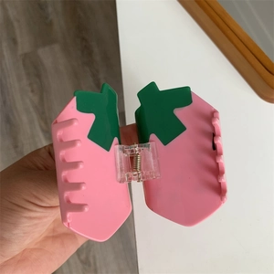 Detail view of a cute pink strawberry hair claw clip with green leaf resin decoration
