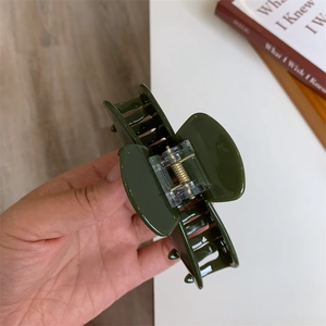 Close-up of a large dark green acetate hair claw clip with a strong metal spring