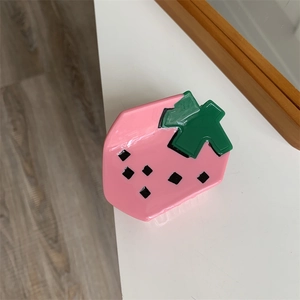 Detailed view of a shiny strawberry hair claw clip made of pink acrylic material