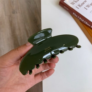 Detail view of large dark green acetate hair claw with golden France lettering engraving