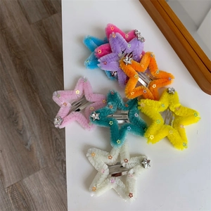 Dettaglio di fermagli per capelli in peluche a stella con paillettes e ciondoli argentati