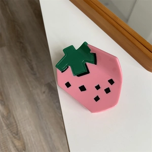 Macro shot of strawberry hair claw clip made of pink acrylic with green leaf detail