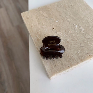 Gros plan sur la petite pince à cheveux ambre foncé avec marquage doré France Handmade