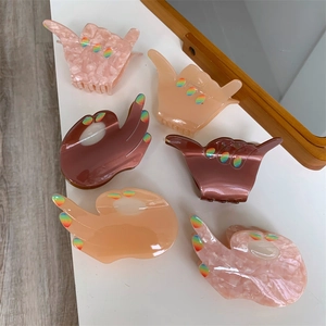Flat lay of acetate gesture hair claws in OK and Shaka shapes with marble textures