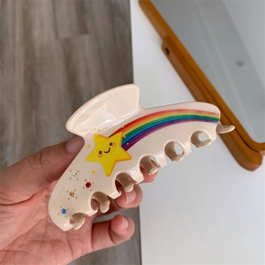 Detailed close-up of a beige star and rainbow acetate hair claw clip with colorful rhinestones