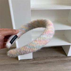 Détail de la texture pelucheuse arc-en-ciel macaron et de l'étiquette Handmade sur le serre-tête