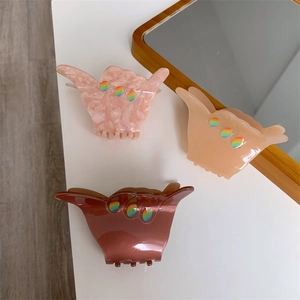 Detailed view of three acetate hair claws featuring a creative Shaka hand gesture design