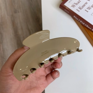 Detail showing high-gloss khaki acetate hair claw with Barrette La France gold lettering
