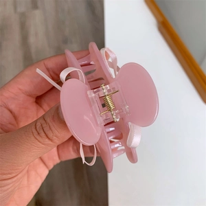 Détail d'une pince à cheveux en acrylique rose translucide avec nœuds en soie