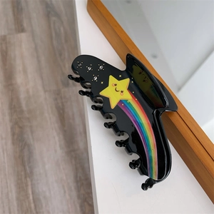 Detail shot of black acrylic hair claw clip featuring yellow star and rainbow pattern
