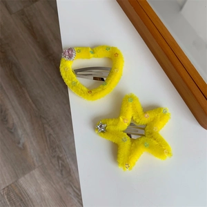Dettaglio di fermagli per capelli in peluche giallo con forme a cuore, stella e strass