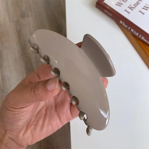 Detailed view of a large acetate hair claw clip in a neutral grey-brown finish