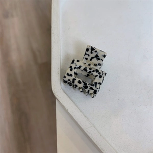 Detail of a spotted black and white acetate hair claw clip with golden France Handmade text