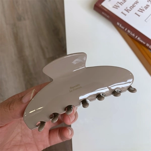 Close-up of a large milk tea brown acetate hair claw clip with gold Barrette La France text